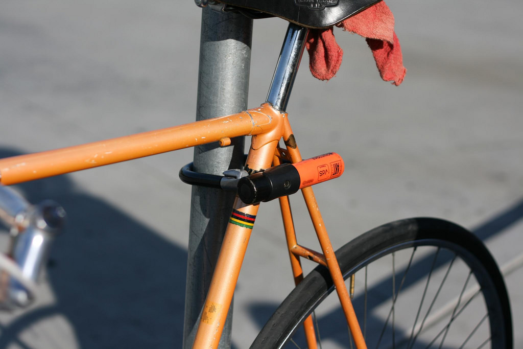 Oranje fiets op slot, de hele ruimte van het slot wordt gebruikt