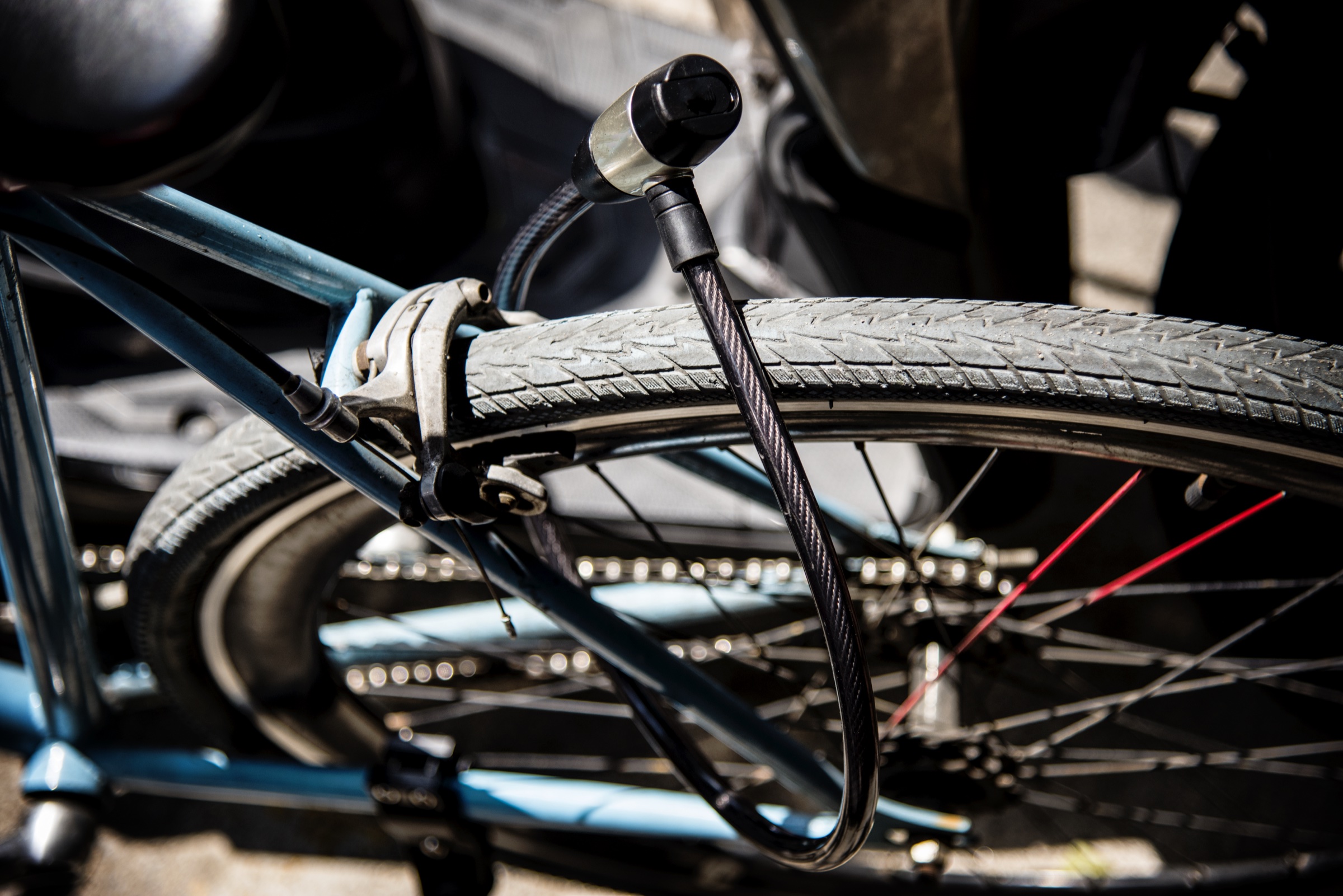 A cable lock through the front wheel and frame of a parked bike