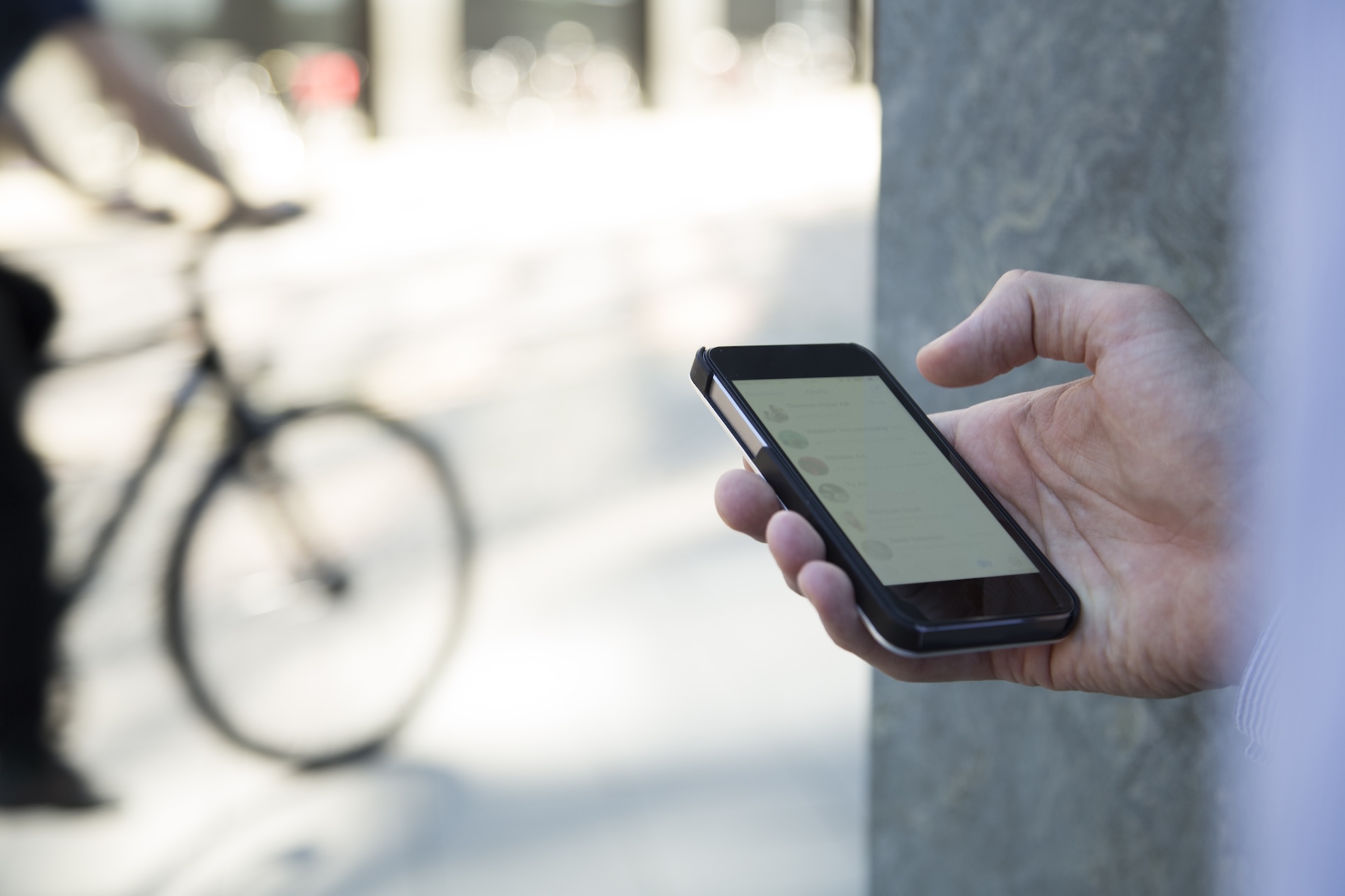 Fietser vergelijkt fietsverzekeringen op smartphone naast zijn fiets